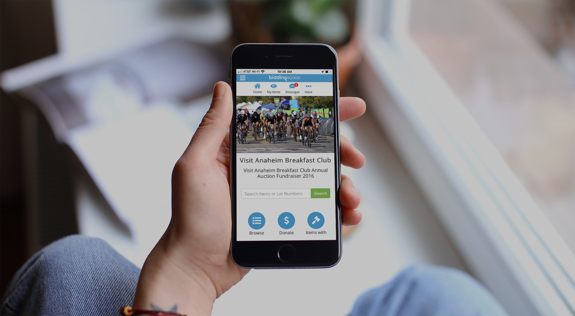 A person's hands holding a mobile phone with BiddingForGood mobile site design on the screen
