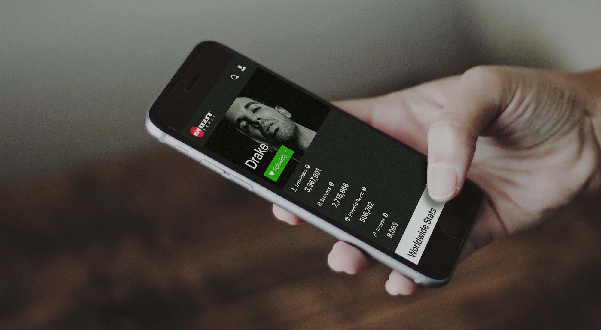 Person holding smart phone with Muzit title details on the screen